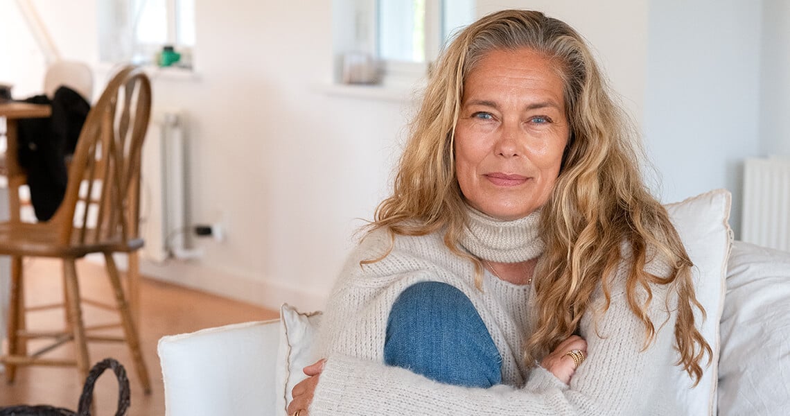 Renée Toft Simonsen sitting in couch hugging her self